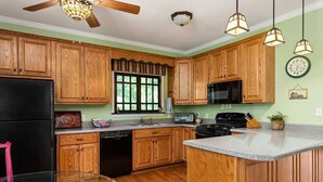 A kitchen with wooden cabinets, a black refrigerator, a microwave, a stove, and a sink.