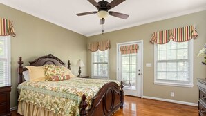 A bedroom with a wooden bed, a ceiling fan, and striped window valances.