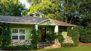 A green house with a stone foundation, a front porch, and a well-maintained lawn.