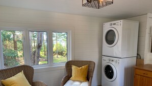 Une buanderie équipée de deux fauteuils en osier, d’un lave-linge et d’un meuble en bois.