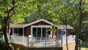 Une terrasse en bois avec une piscine, entourée d’arbres.