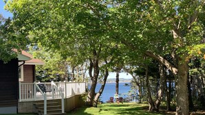 Une terrasse en bois avec une balustrade blanche, un petit bâtiment et une vue sur un lac.