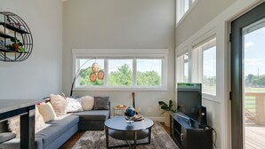 A modern living room with a grey sofa, a round coffee table, and a TV stand. - Perfect Downtown Views for the 4th of JULY / Watch FIREWORKS from private deck (Nashville)