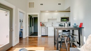 A modern kitchen with white cabinets, a microwave, and a coffee maker. There is a dining area with stools and a small table. - Perfect Downtown Views for the 4th of JULY / Watch FIREWORKS from private deck (Nashville)