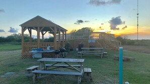 A gazebo with picnic tables and a barbecue grill in a grassy area. - JJB Cabins (Matagorda)