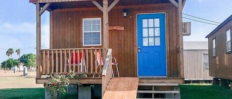 A small wooden building with a blue door, a ramp leading to the entrance, and a sign that reads "FISHING MISSION".