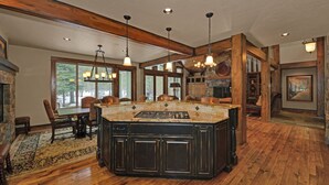 A spacious kitchen with a large island, wooden beams, and pendant lighting. - Beautiful Sunriver Lodge Home steps to the Deschutes (Sunriver)