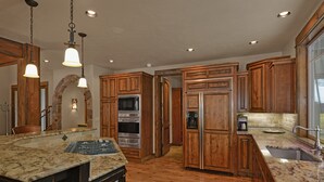 A kitchen with wooden cabinets, granite countertops, a built-in oven, and a stainless steel refrigerator. - Beautiful Sunriver Lodge Home steps to the Deschutes (Sunriver)