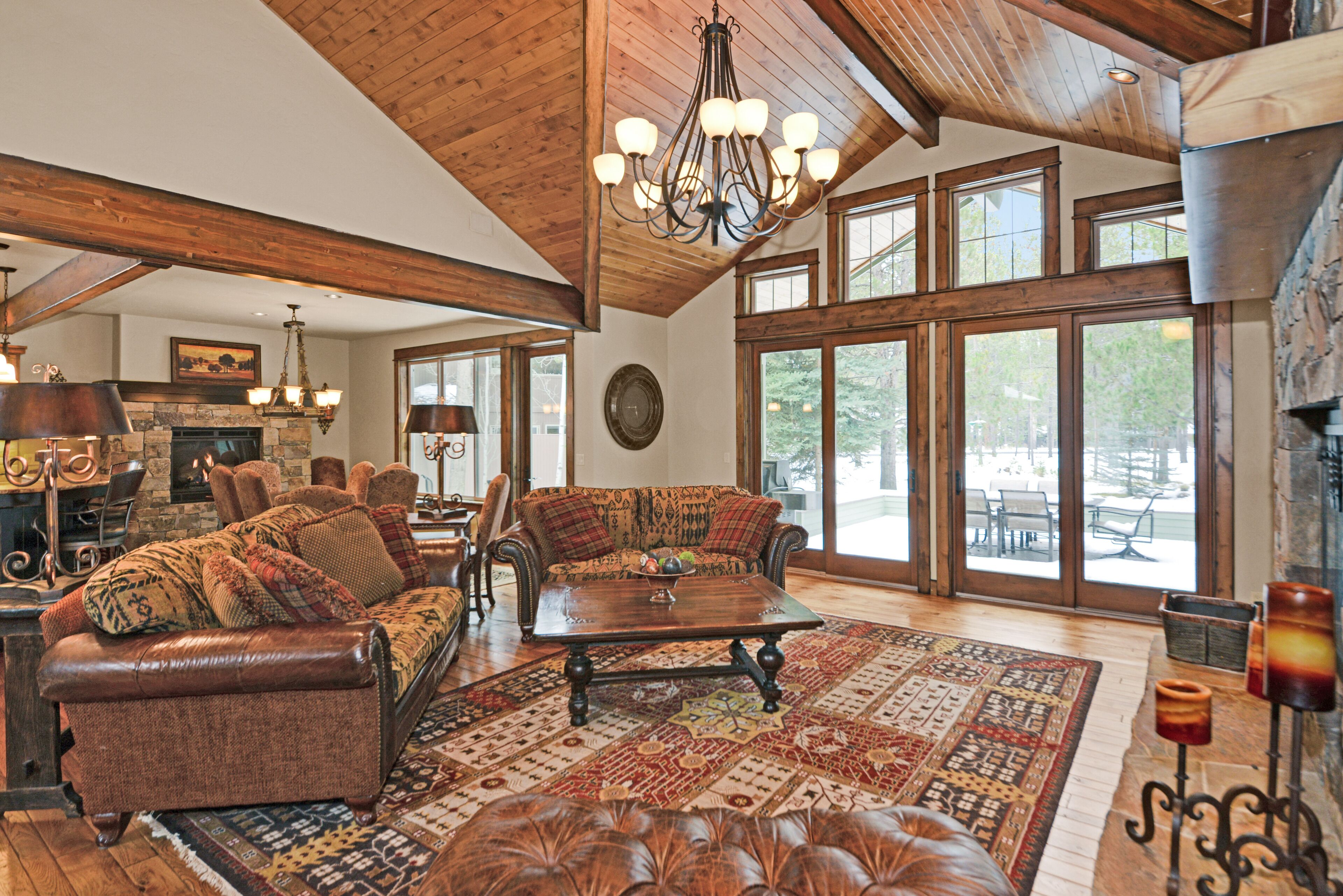 A spacious living room with a fireplace, leather furniture, and large windows.