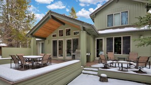 A two-story house with a covered patio area featuring outdoor furniture and a grill. - Beautiful Sunriver Lodge Home steps to the Deschutes (Sunriver)