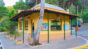 A small yellow building with a tiled roof, a bench, and a map on the wall.