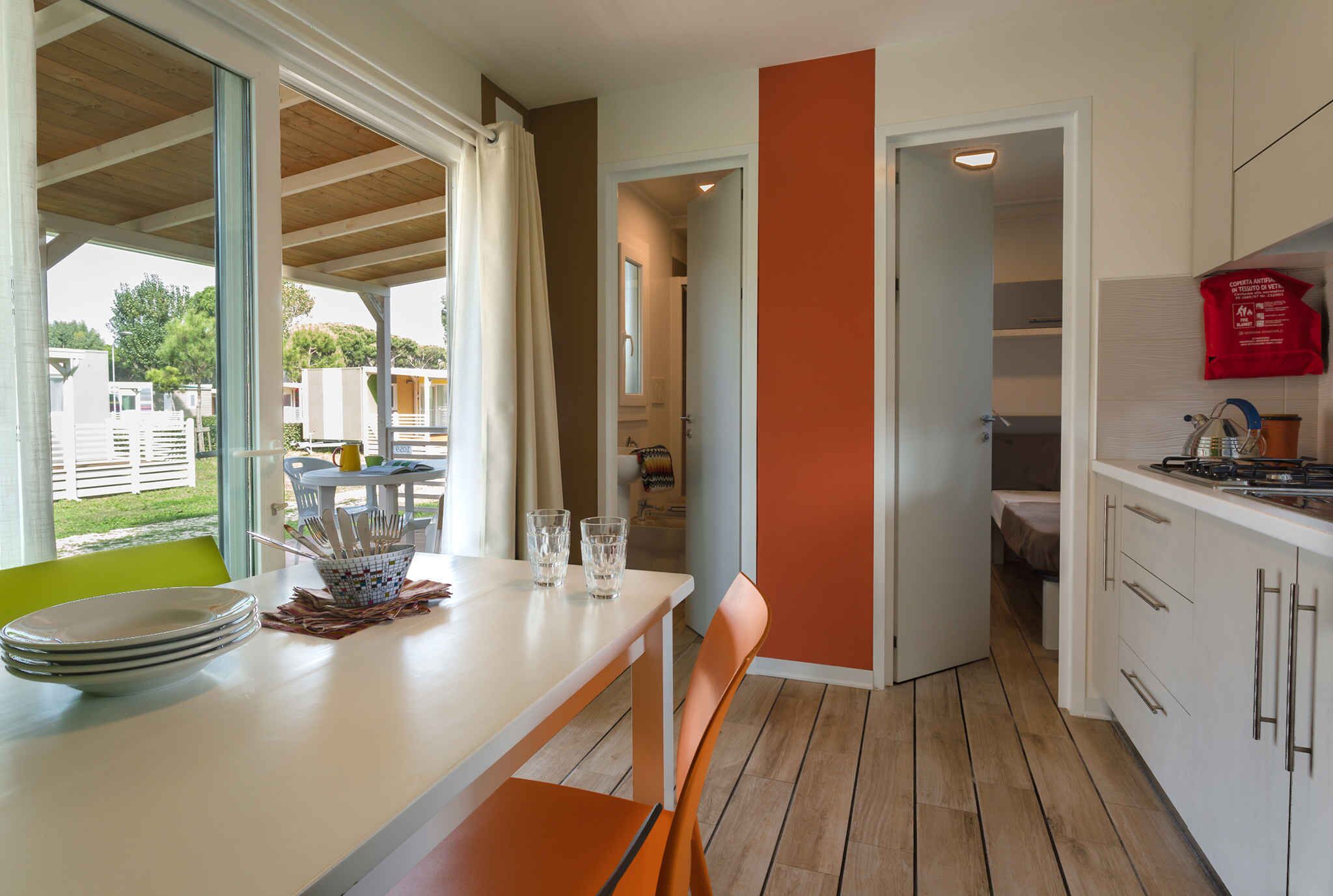 A modern kitchen with white cabinets, a dining area with a table and chairs, and a view of the outside.