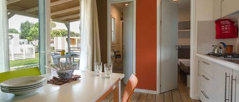 A modern kitchen with white cabinets, a dining area with a table and chairs, and a view of the outside.