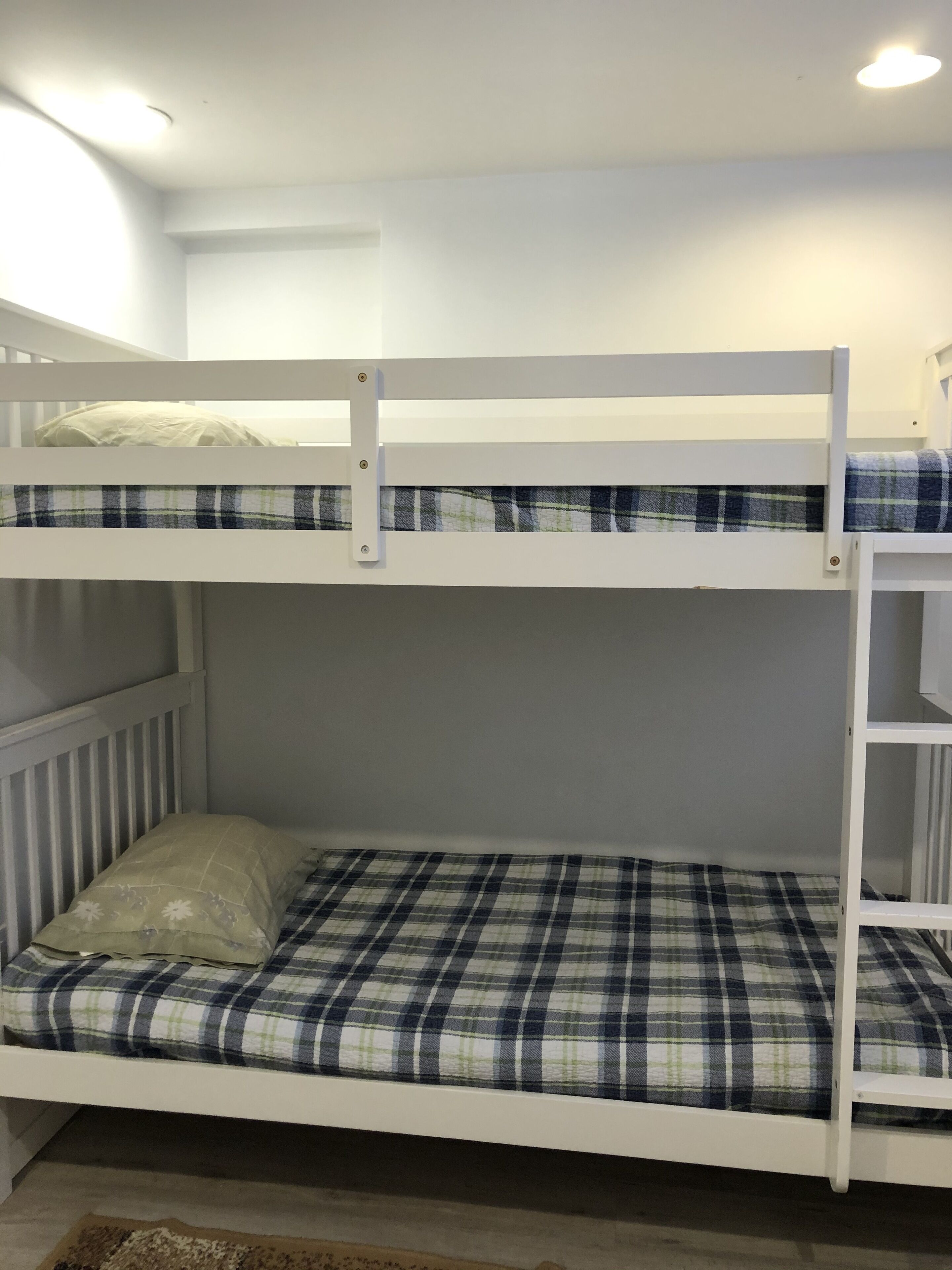 A bunk bed with a plaid bedspread and a pillow.