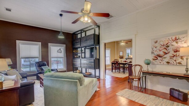 A spacious living room with a sofa, a dining area with a table and chairs, a bookshelf, and a ceiling fan. - Charming Southern Bungalow Convenient to Savannah (Bloomingdale)