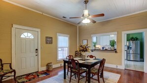 A dining area with a wooden table and chairs, a ceiling fan, and a window with a view of the outside. - Charming Southern Bungalow Convenient to Savannah (Bloomingdale)