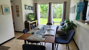 A dining area with a long table, chairs, and a television on a stand. - Playa Bejuco 3-bdrm home in beachfront condominium (Playa Bejuco)