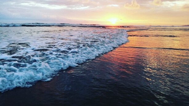 A beach with waves at sunset.