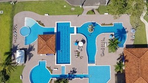 An aerial view of a resort with multiple swimming pools, palm trees, and a road nearby. - Playa Bejuco 3-bdrm home in beachfront condominium (Playa Bejuco)