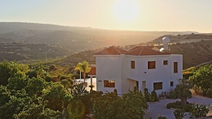 A white building with a red-tiled roof, surrounded by greenery and hills. - Skouli: A traditional property in Skoulli, near Polis, with heated pool (Polis)