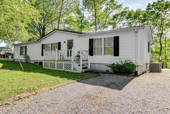 Ein Bungalowmobilheim mit Veranda, einer kleinen Terrasse und einer Zuwegung mit Kies.