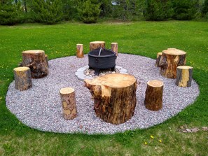 Un espacio de asientos circular con una fogata rodeada de troncos de madera y grava.