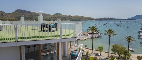 Un balcon à plusieurs niveaux, doté d’un espace extérieur aménagé, qui offre une vue sur une marina et les bateaux qui y sont amarrés.