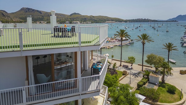 A multi-story building with a balcony overlooking a marina and the sea.