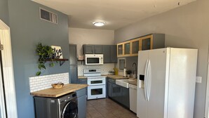 Eine kleine Küche mit Waschmaschine, Mikrowelle, Backofen und Kühlschrank.