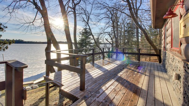A wooden deck with a view of a lake and trees. - Cozy Cabin w/ Private Dock on Fifth Crow Wing Lake (Nevis)
