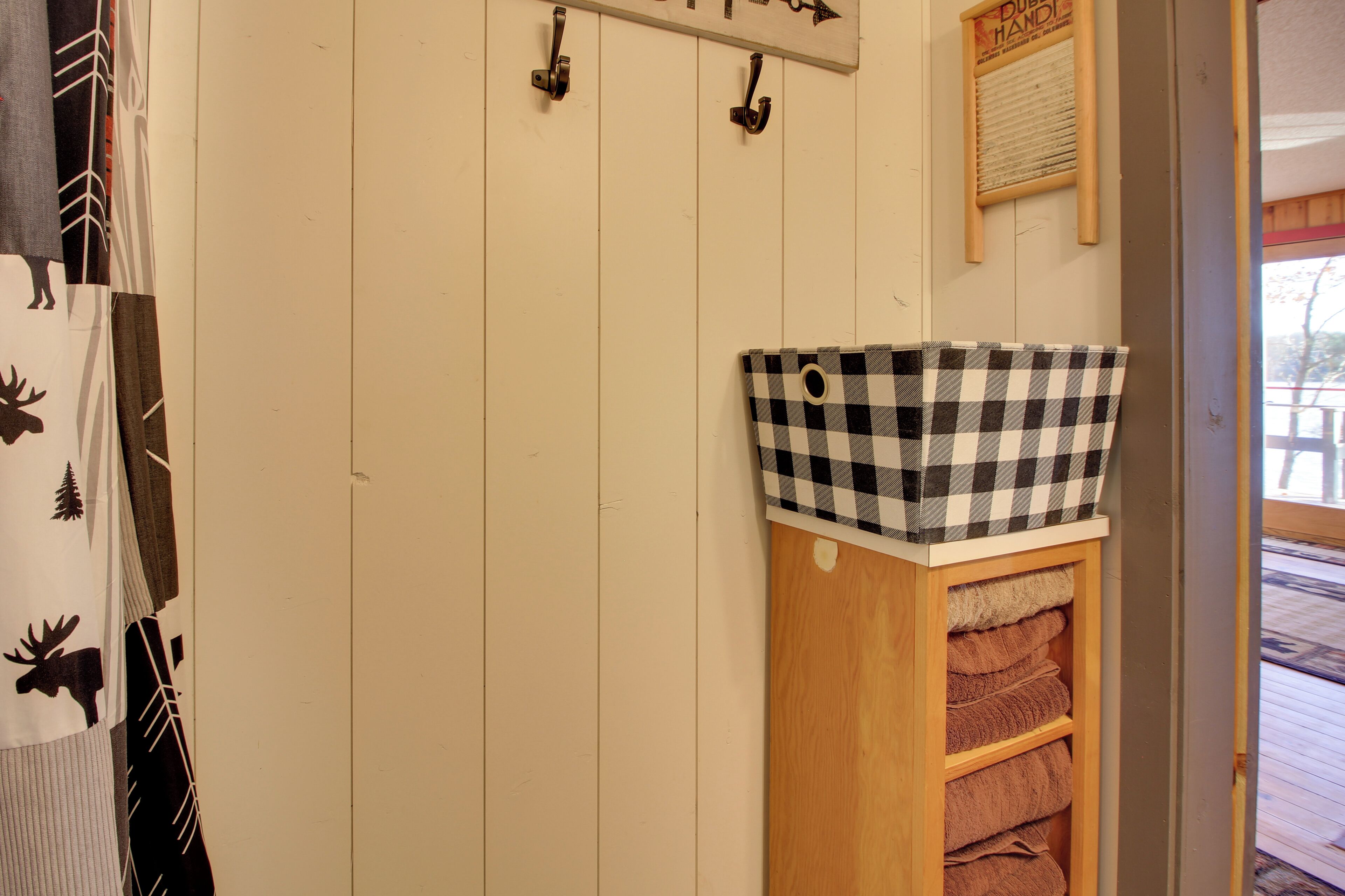 A wooden shelf with a checkered basket and towels.