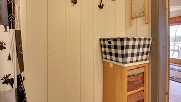 A wooden shelf with a checkered basket and towels.