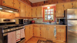 A kitchen with wooden cabinets, a stove, a microwave, and a refrigerator. - Cozy Cabin w/ Private Dock on Fifth Crow Wing Lake (Nevis)