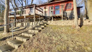 A cabin with a wooden exterior, a stone foundation, and a staircase leading to a deck. - Cozy Cabin w/ Private Dock on Fifth Crow Wing Lake (Nevis)