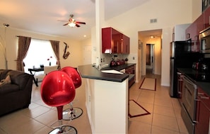 A modern kitchen with red cabinets, a central island, and a dining area with red chairs. - Red Corvette House with Theater Room - WR001 (Davenport)
