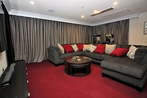 A living room with a sectional sofa, a glass coffee table, and a red carpet. - Red Corvette House with Theater Room - WR001 (Davenport)