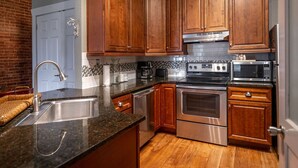 Una cocina con armarios de madera, electrodomésticos de acero inoxidable y encimera de granito.