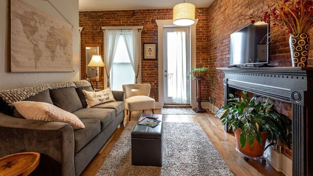Una sala de estar con pared de ladrillo, un sofá, un televisor y una chimenea.