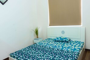 Cozy retreat with a single bed, floral-patterned bedspread, and a potted plant on a nightstand.
