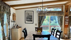 A dining area with a table set for four, a chandelier, and a view of the outdoors. - Log Cabin Near Hunter Mountain (Hunter)