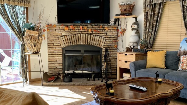 A cozy living room with a fireplace, a television mounted above it, and a comfortable sofa. - Log Cabin Near Hunter Mountain (Hunter)