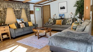 A cozy living room with a grey sofa, a wooden coffee table, and a grey furry rug. - Log Cabin Near Hunter Mountain (Hunter)
