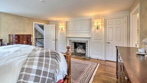 A bedroom with a large bed, a fireplace, a dresser, and a nightstand. - Spacious Estate w/ Courtyard: 2 Miles to Downtown! (Keene)