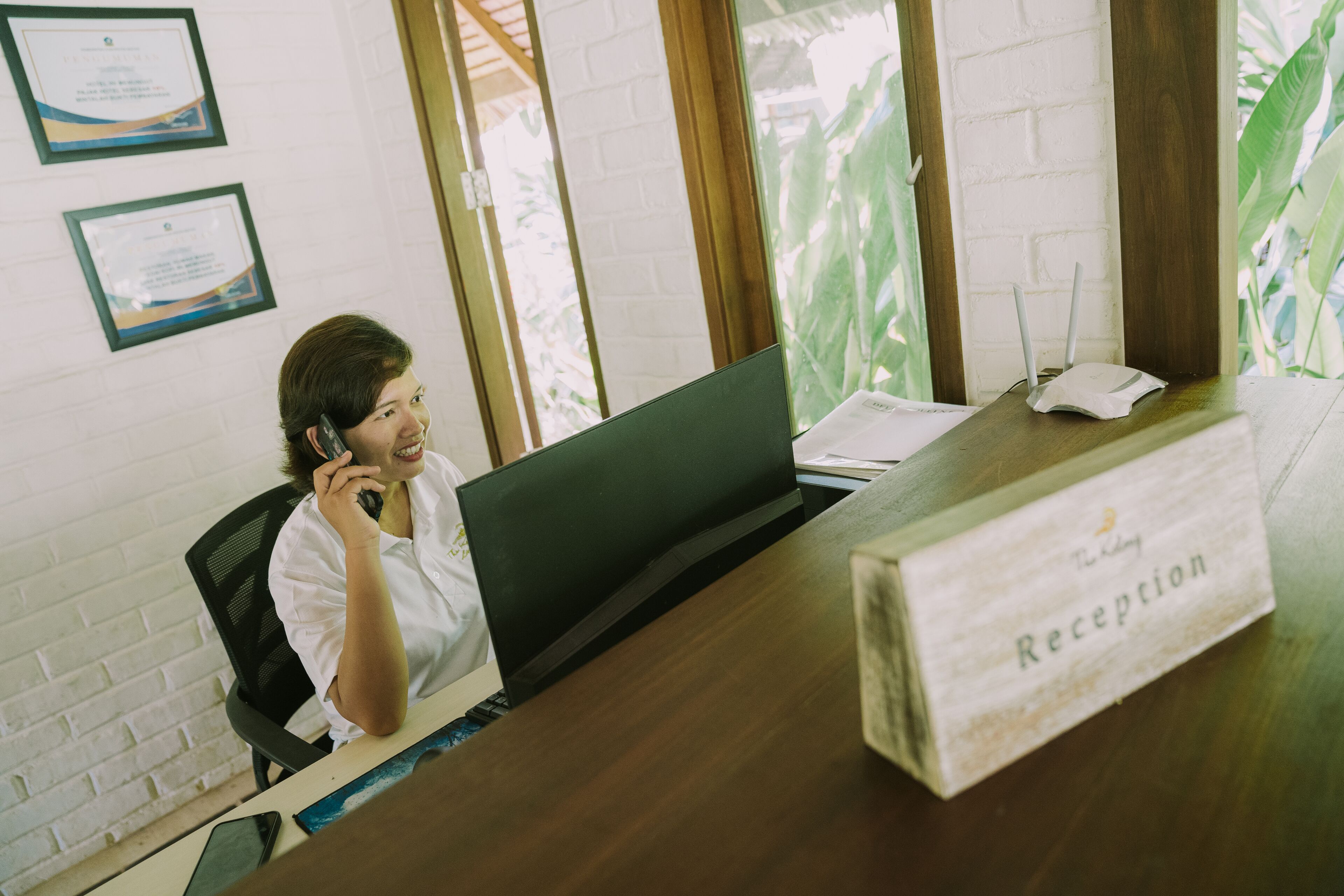A reception desk with a sign labeled "Reception" and a laptop on the desk.