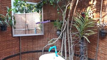 Casa de banho com lavatório, espelho e planta suspensa.