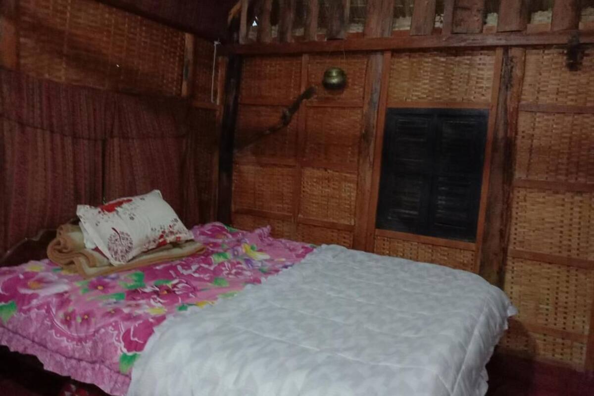 Une pièce en bois avec un lit, une porte en bois et un mur orné d’un motif tissé.