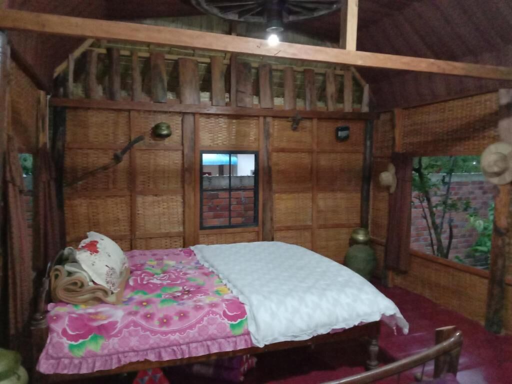 A rustic wooden room with a bed, a small window, and a decorative vase.