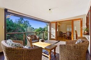 Un balcón con mobiliario de mimbre, una mesa de madera y vistas al exterior.