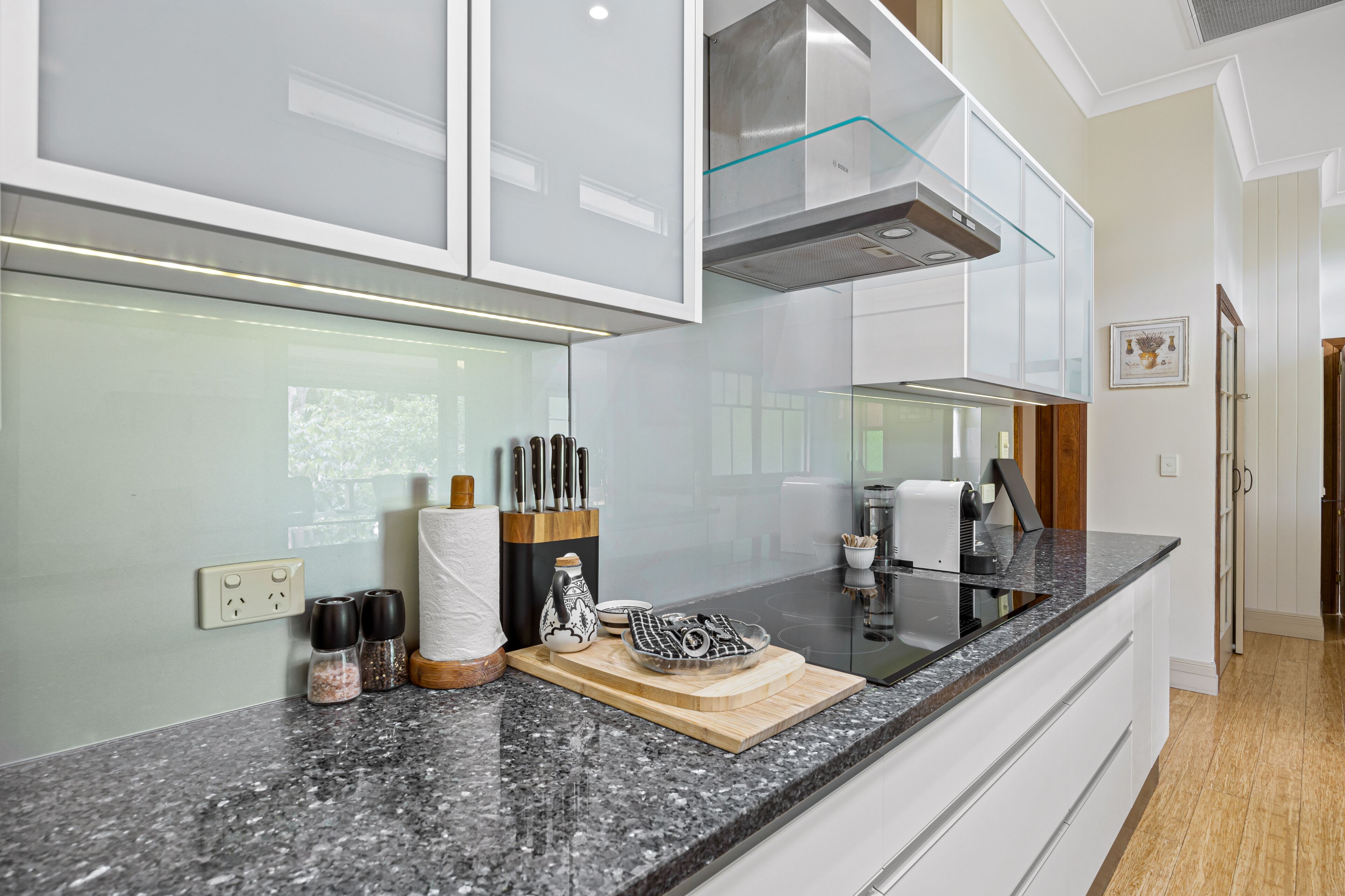 A modern kitchen with a granite countertop, stainless steel appliances, and a wooden cutting board.