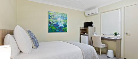 Un dormitorio con cama, escritorio, silla, ventilador de techo y aire acondicionado.